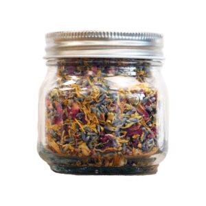 Borcan din sticlă cu amestec facial botanic pentru abur având flori uscate multicolore vizibile în interior pe fundal alb